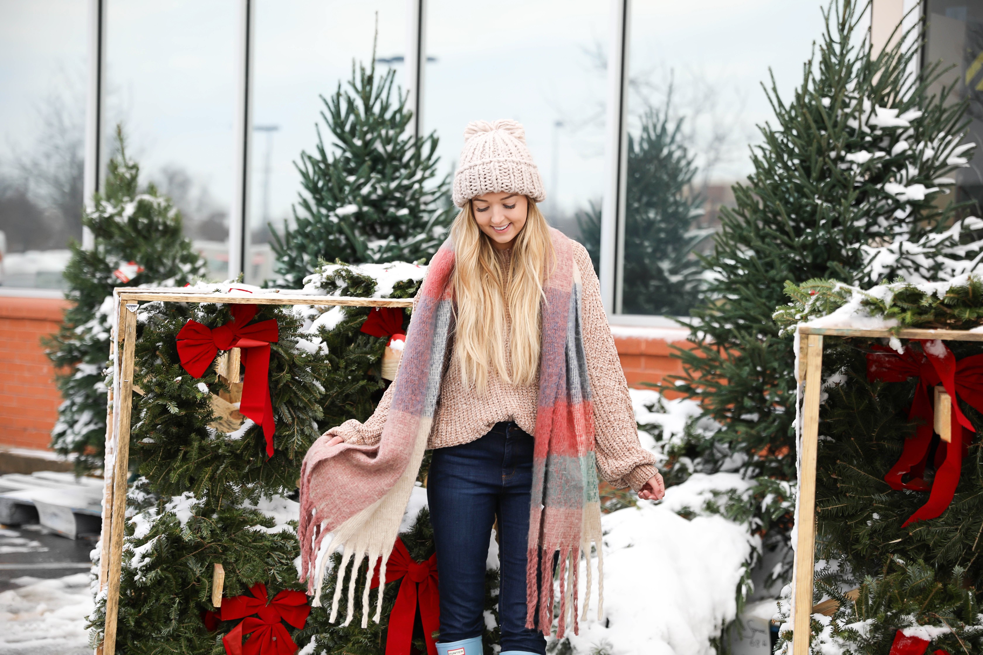 The cutest winter look! I am wearing this super cozy knit beanie, chenille sweater, blue hunter boots, and plaid heavy scarf! I love winter outfits! Photoshoot at a christmas wreath store! Holiday outfit idea on fashion blog daily dose of charm by lauren lindmark