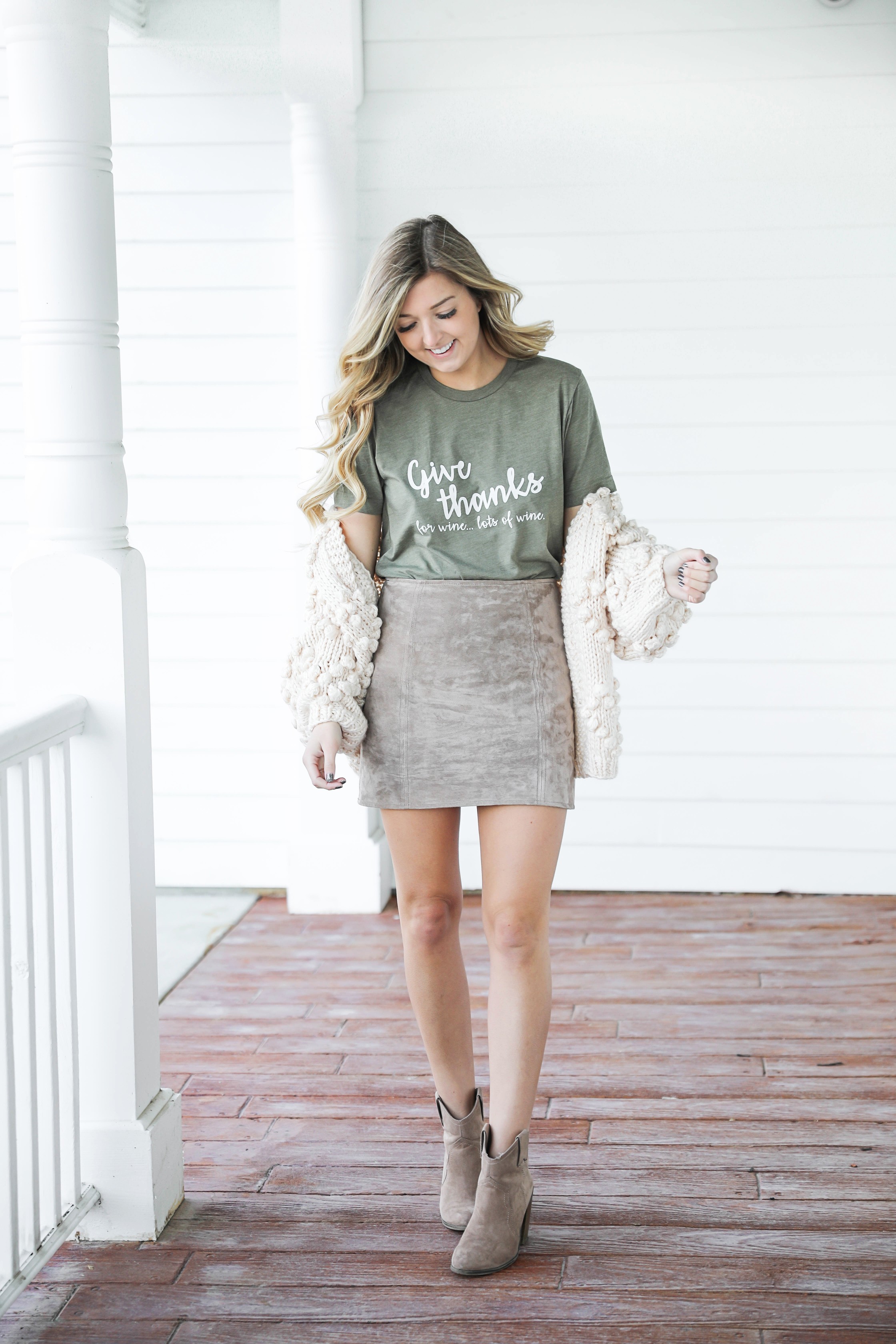 Thanksgiving outfit idea! Thanksgiving look, I love this t-shirt that says thankful for wine! The olive color shirt is so cute for this time of year and looks so good with the suede skirt and pom cardigan! Details on fashion blog daily dose of charm by lauren lindmark