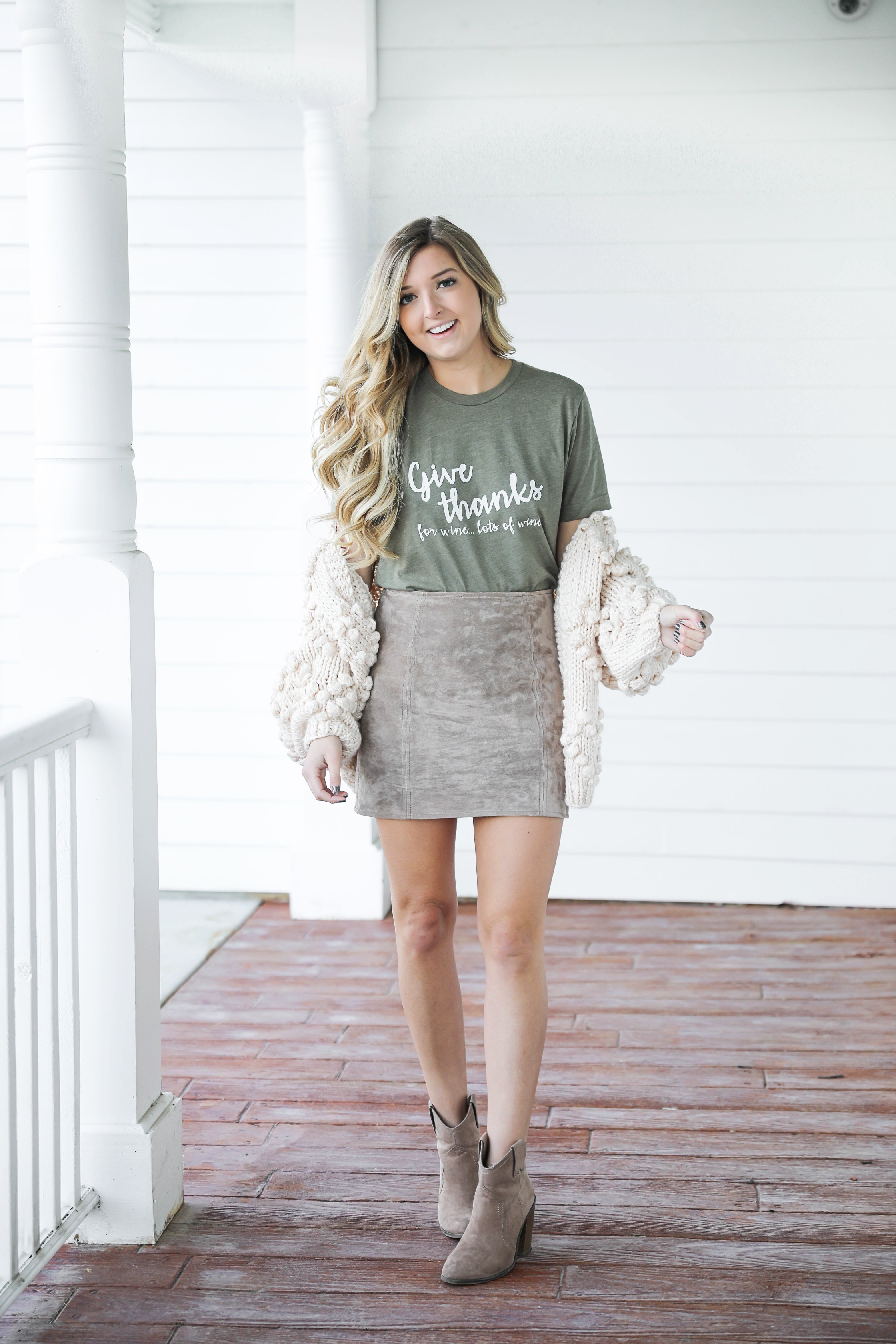 Thanksgiving outfit idea! Thanksgiving look, I love this t-shirt that says thankful for wine! The olive color shirt is so cute for this time of year and looks so good with the suede skirt and pom cardigan! Details on fashion blog daily dose of charm by lauren lindmark