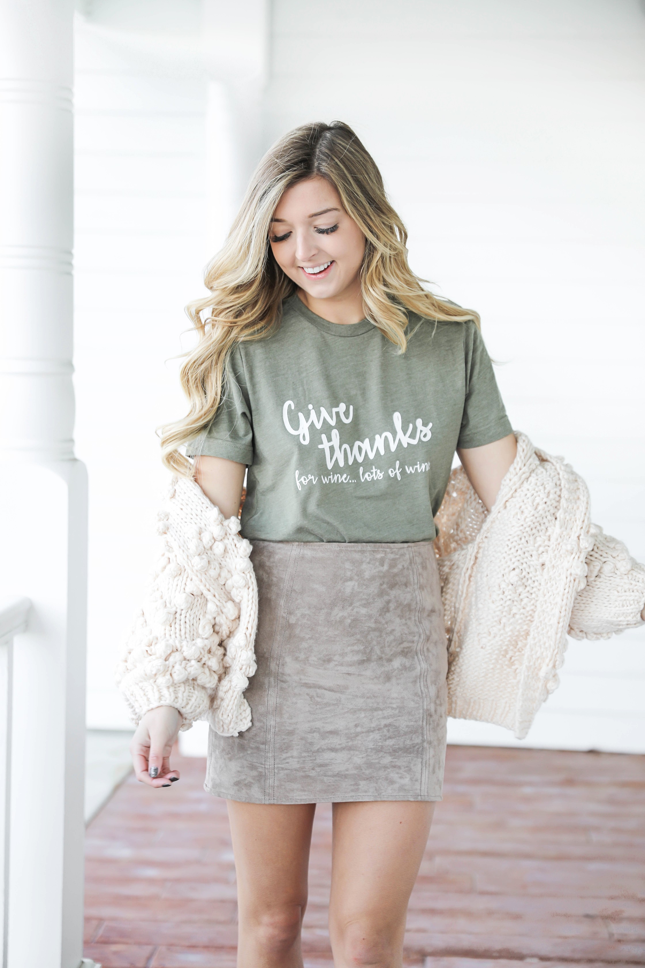 Thanksgiving outfit idea! Thanksgiving look, I love this t-shirt that says thankful for wine! The olive color shirt is so cute for this time of year and looks so good with the suede skirt and pom cardigan! Details on fashion blog daily dose of charm by lauren lindmark