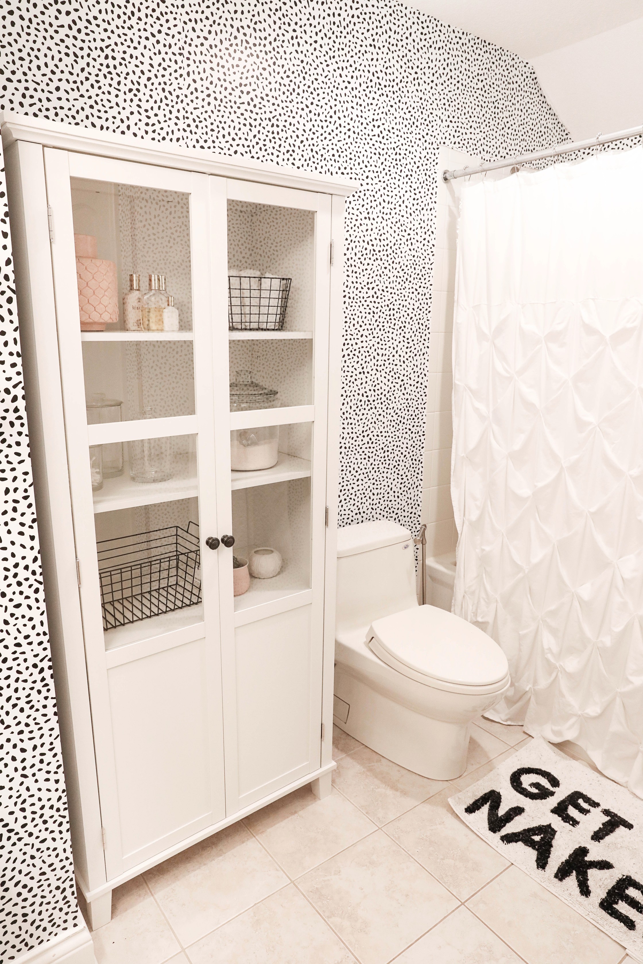 Bathroom transformation! The before photo of this bathroom are horrible, such an ugly blue color! I switched it up with some cute black and white Dalmatian wallpaper! This wallpaper is completely temporary and removable which makes it great for renting! Such a cute interior design post! Cutest black and white bathroom! Details on lifestyle and fashion blog daily dose of charm by lauren lindmark