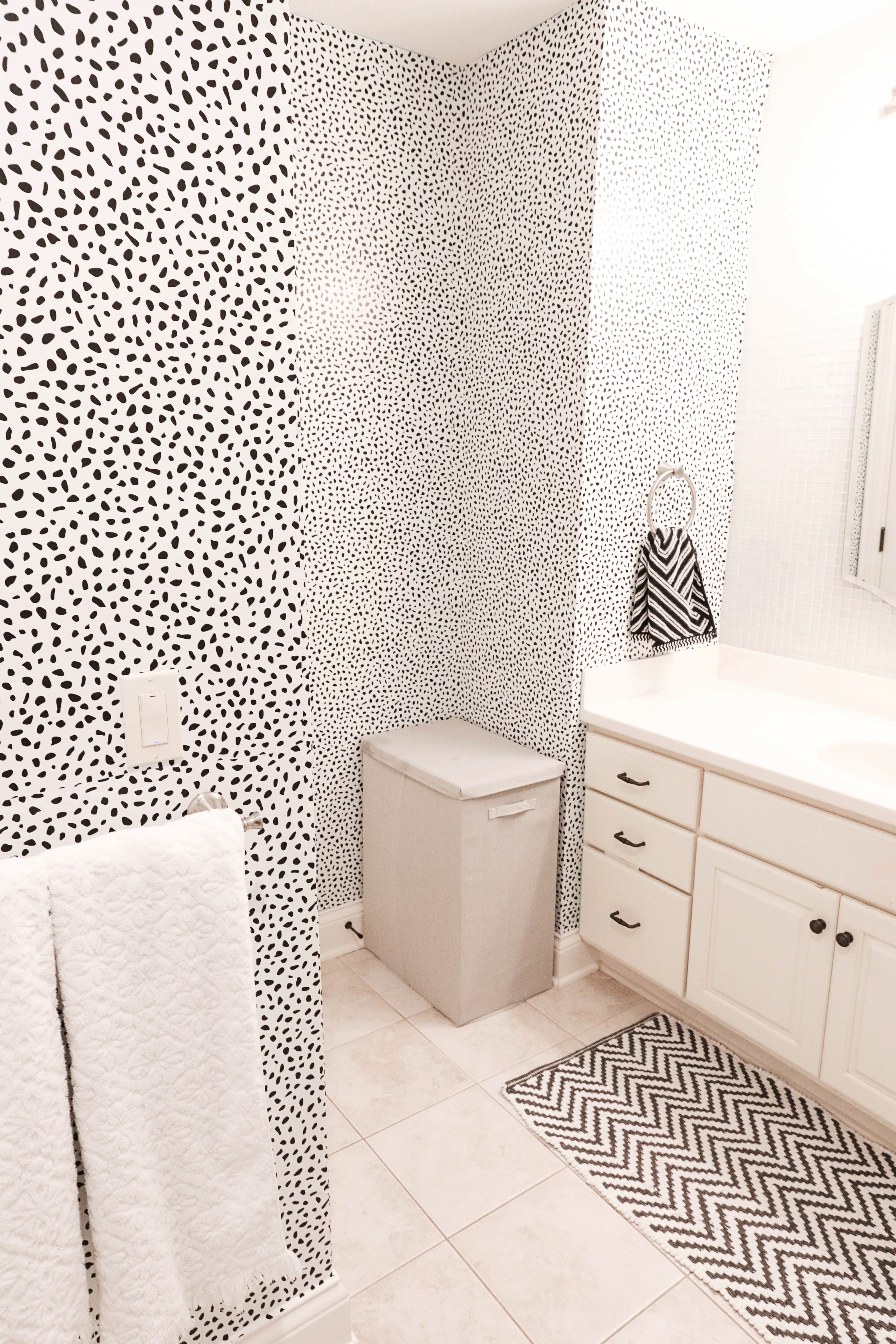 Bathroom transformation! The before photo of this bathroom are horrible, such an ugly blue color! I switched it up with some cute black and white Dalmatian wallpaper! This wallpaper is completely temporary and removable which makes it great for renting! Such a cute interior design post! Cutest black and white bathroom! Details on lifestyle and fashion blog daily dose of charm by lauren lindmark