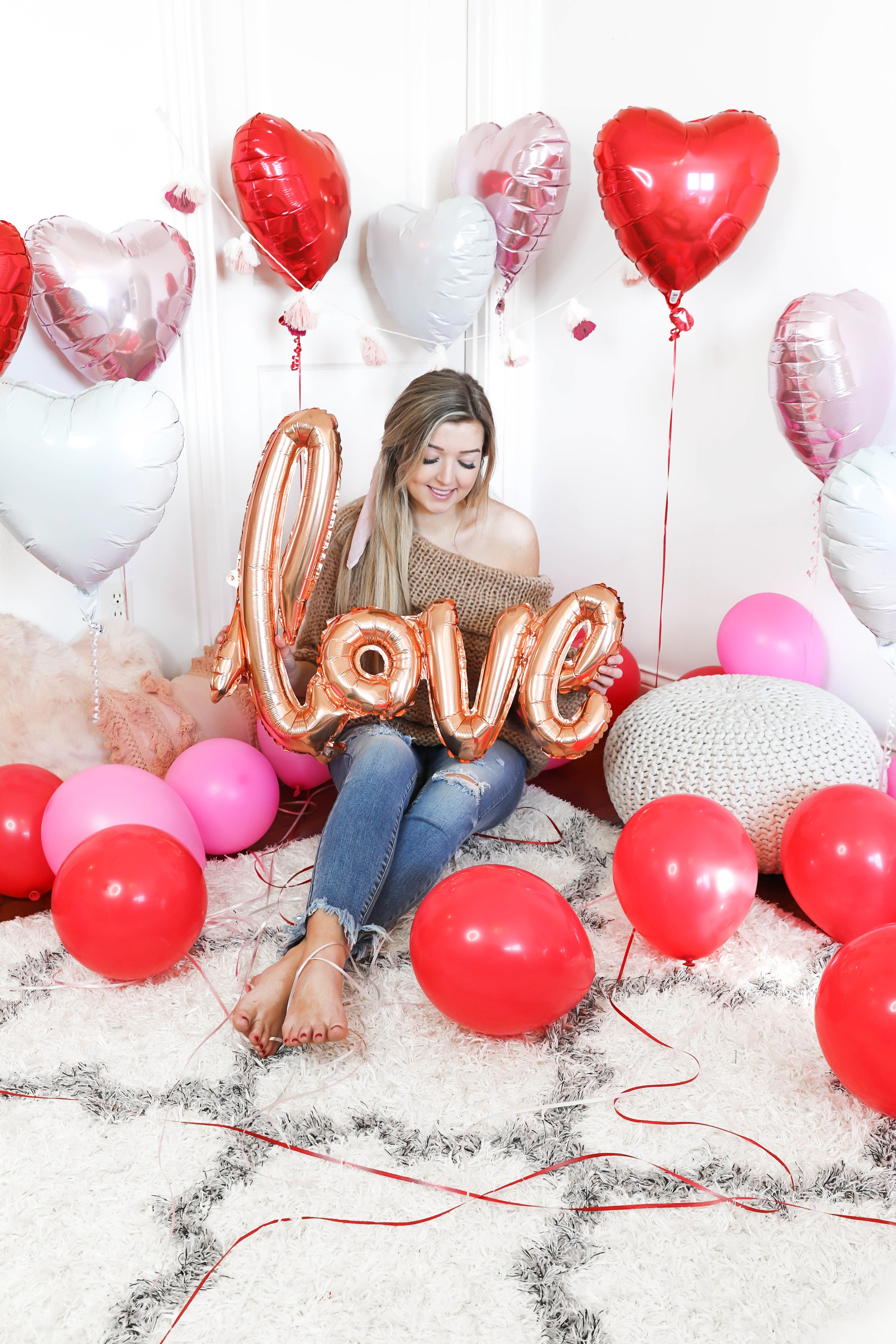 Valentine's Day shoot with the cutest heart shaped balloons and pink and red decor! My cute little pomeranian puppy dog made an appearance in the pics! I am wearing the cutest, tan, off the shoulder sweater from amazon and the cutest ripped denim from Red Dress Boutique! Details on style and fashion blog daily dose of charm by lauren lindmark