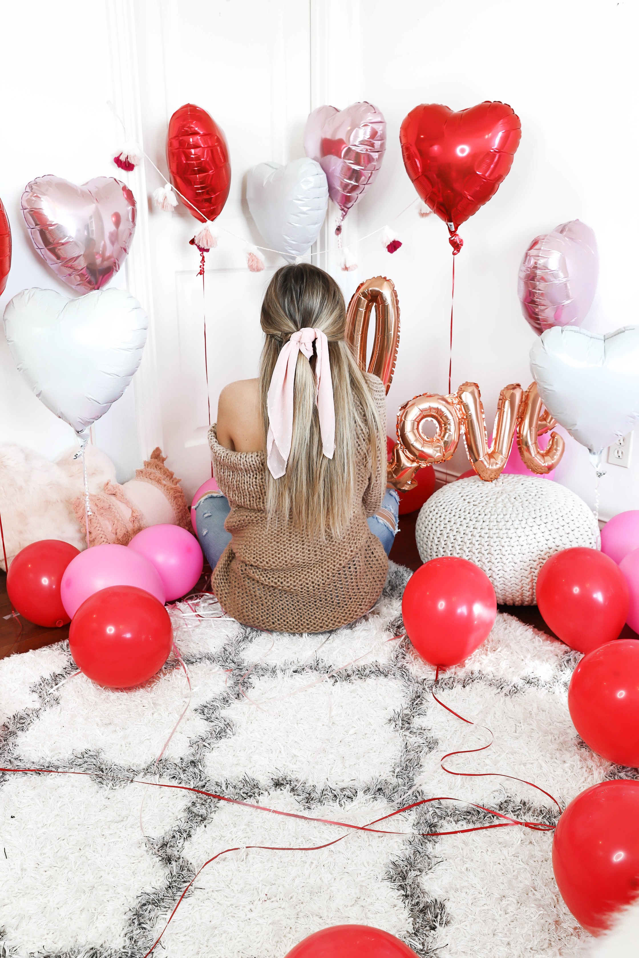 Valentine's Day shoot with the cutest heart shaped balloons and pink and red decor! My cute little pomeranian puppy dog made an appearance in the pics! I am wearing the cutest, tan, off the shoulder sweater from amazon and the cutest ripped denim from Red Dress Boutique! Details on style and fashion blog daily dose of charm by lauren lindmark