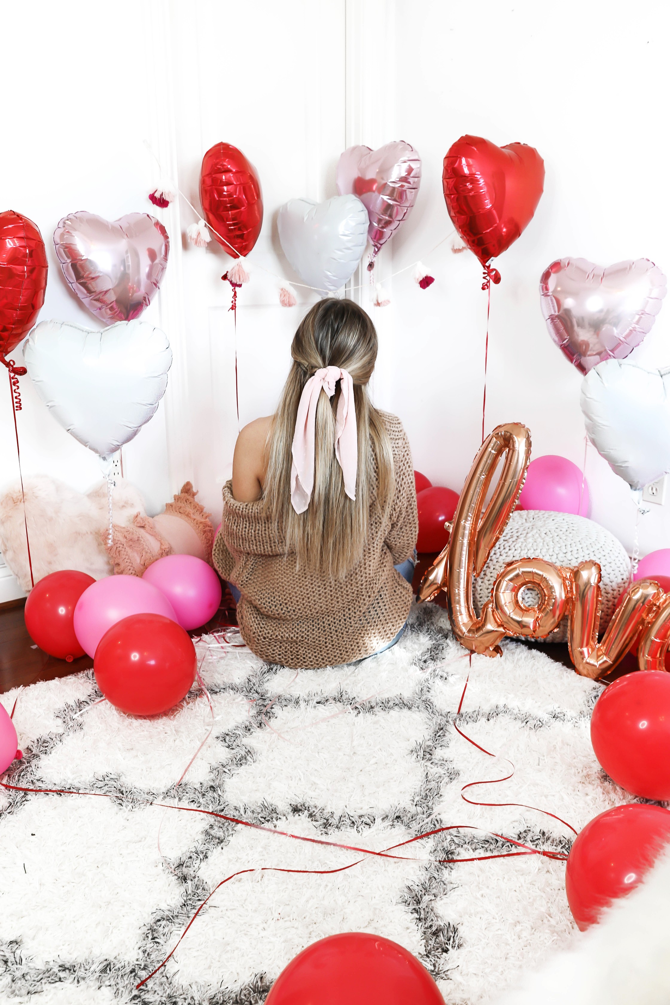 Valentine's Day shoot with the cutest heart shaped balloons and pink and red decor! My cute little pomeranian puppy dog made an appearance in the pics! I am wearing the cutest, tan, off the shoulder sweater from amazon and the cutest ripped denim from Red Dress Boutique! Details on style and fashion blog daily dose of charm by lauren lindmark